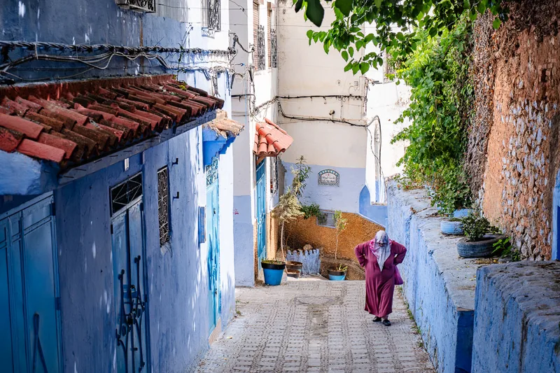 A narrow lane in Chefchaouen washed entirely in shades of blue, a single figure walking away