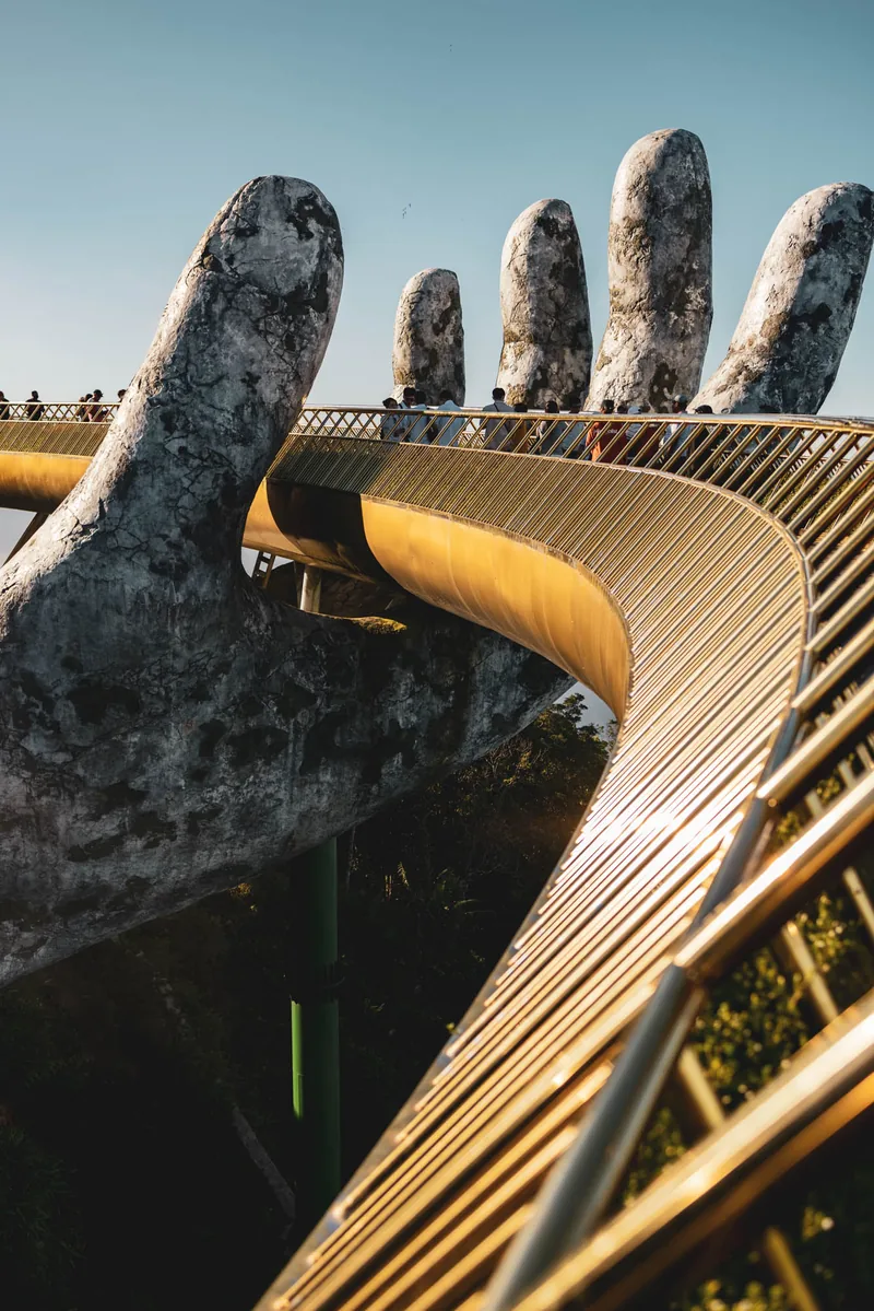 The Golden Bridge held aloft by two giant stone hands, curving away into mountain mist