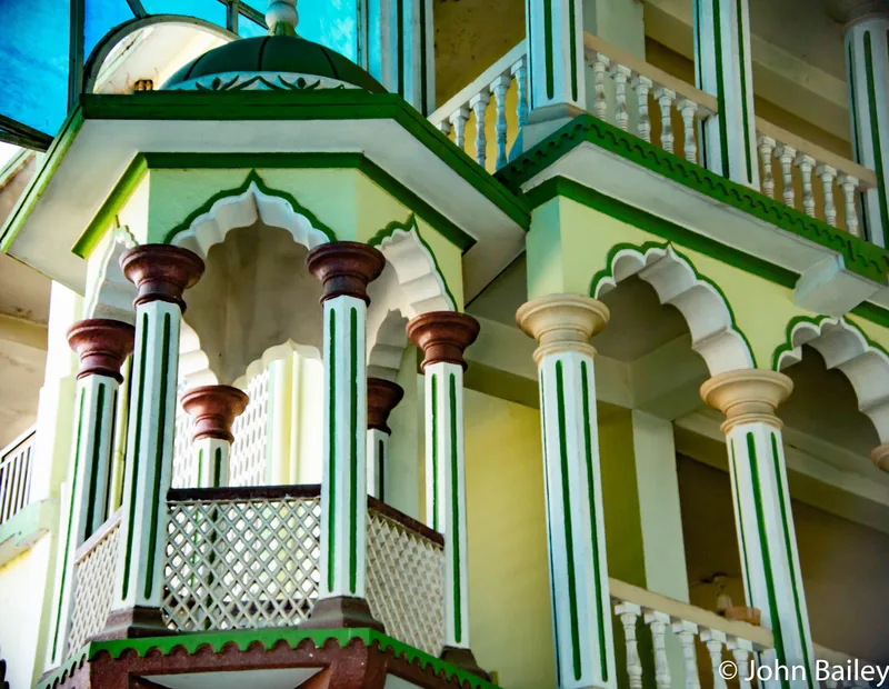 An ornate mosque facade in pale green and white, arches and slender columns in symmetry