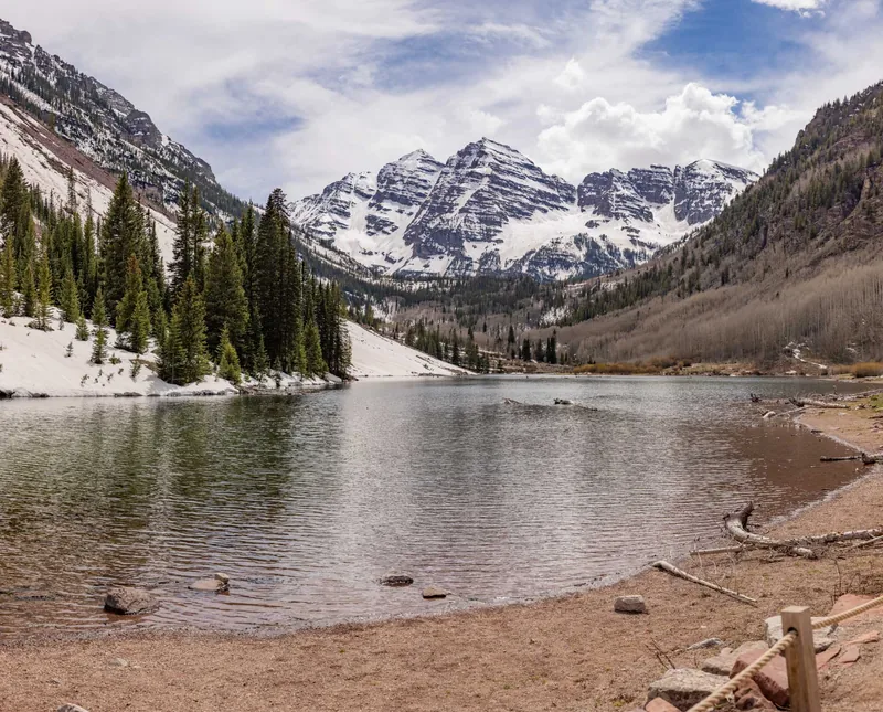 The Maroon Bells peaks under fresh snow, mirrored in the glassy surface of Maroon Lake