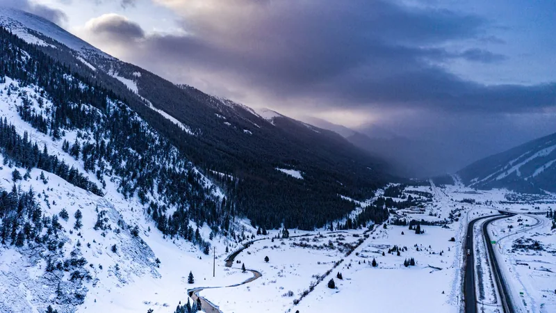 Aerial view of a deep snow-filled valley with a single track running through it at dusk