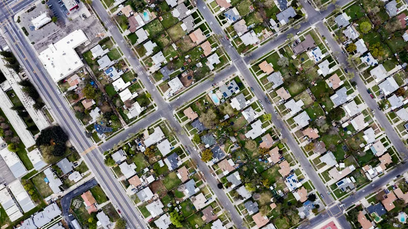 Straight-down aerial view of a suburban street grid, rooftops and trees in perfect order