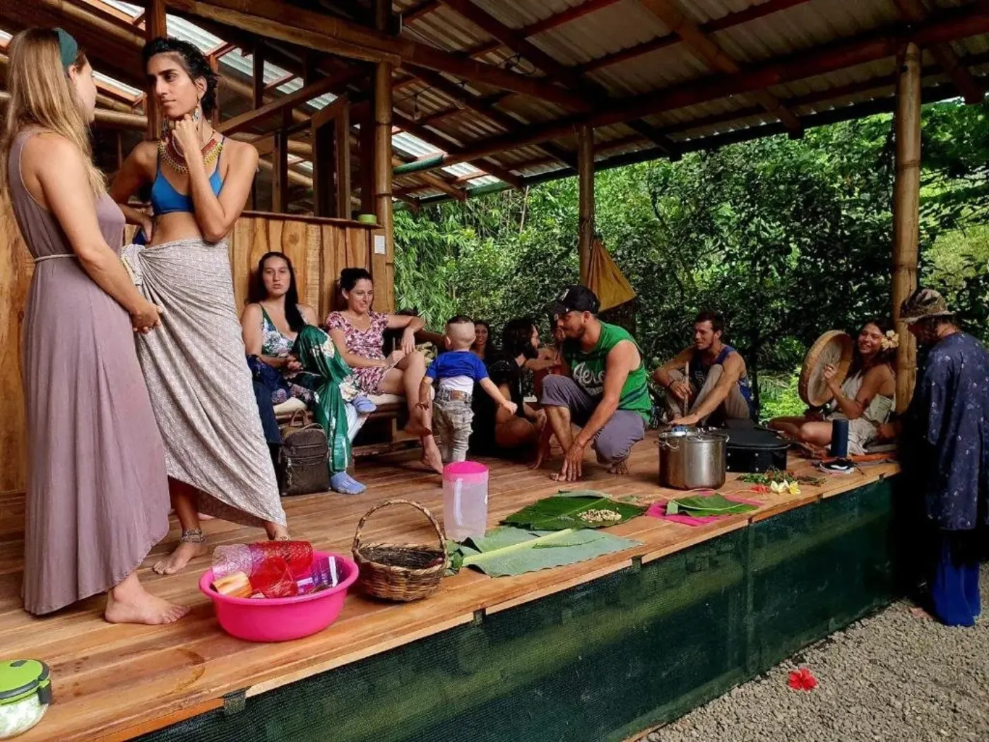 The open-air lodge with people gathered around food on banana leaves